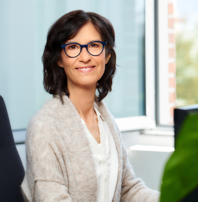 Dunkelhaarige Frau mit Brille am Computer sitzend